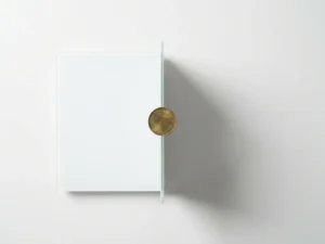 Messing munt in balans op rand van minimalistische witte weegschaal, dramatische schaduw op matte ondergrond, warm goud en zacht grijs.