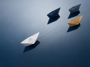 Origami papieren bootje vaart rechtdoor op reflecterend oppervlak, andere bootjes drijven af op achtergrond, marineblauw en zandtinten
