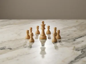 Witte schaakkoning omringd door pionnen in beschermende formatie op marmeren oppervlak met lange schaduw